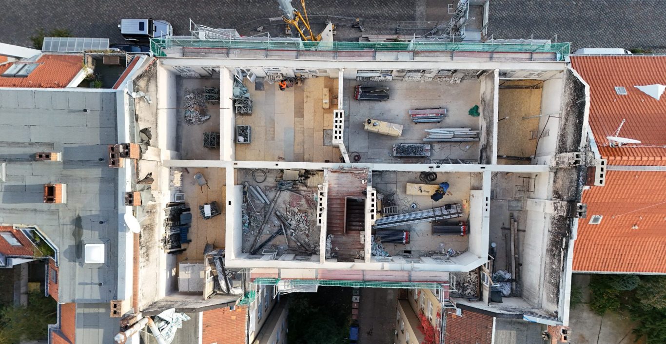 Blick von oben auf eine Baustelle mit Baumaschinen von einem Mehrfamilienhaus in Berlin.